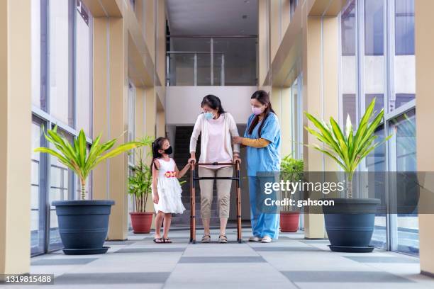 gardienne aidant une femme âgée avec la marche à mobilité réduite, petite-fille soutenant la grand-mère - elderly care japanese photos et images de collection