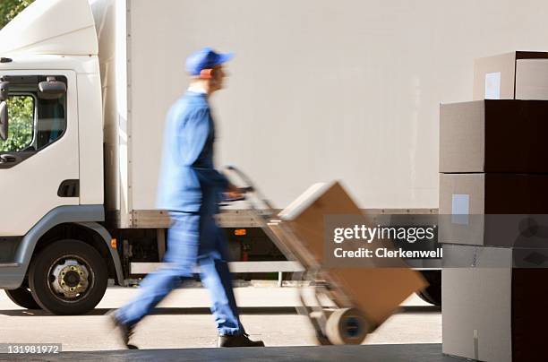 side view of worker with push cart outside warehouse - hand truck stock pictures, royalty-free photos & images