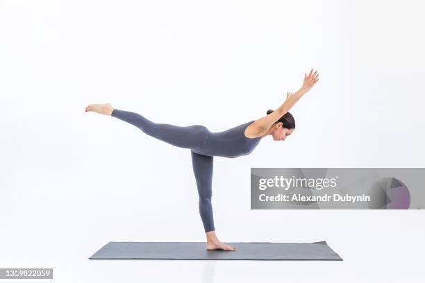 woman practicing sports yoga while standing on the mat on a white background. person doing stretching - trainer cutout stockfoto's en -beelden