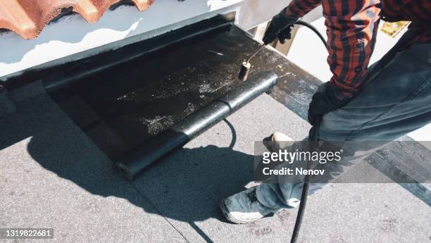 roofer preparing part of bitumen roofing felt roll for melting by gas heater torch flame - waterproof photos et images de collection