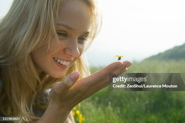 young woman holding ladybug as it takes off in flight - marienkäfer stock-fotos und bilder