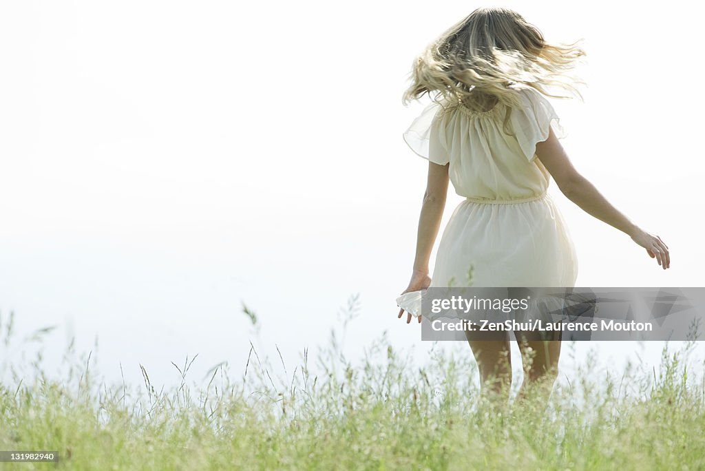 Young woman jumping in meadow, rear view