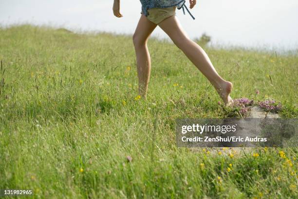 woman running on meadow with bare feet, low section - pantalón corto fotografías e imágenes de stock