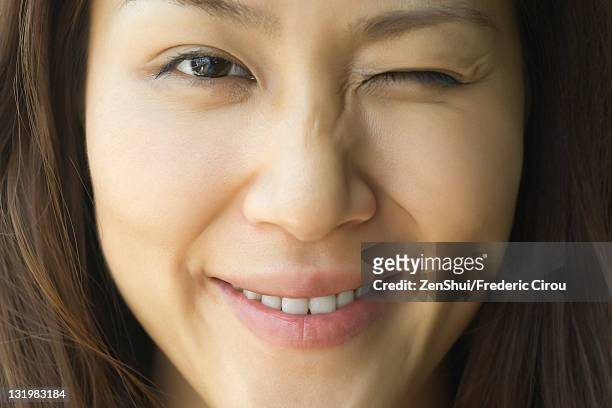 young woman winking, cropped - winking stock pictures, royalty-free photos & images