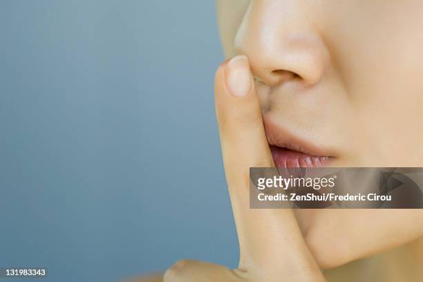 young woman with finger held to lips, cropped - callar fotografías e imágenes de stock