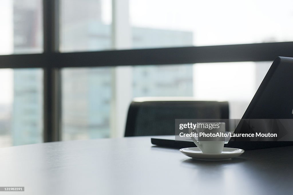 Laptop computer and coffee cup and saucer