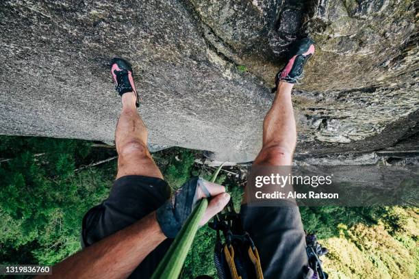 pov photo of rock climber rappelling down a 300 meter tall rock face - klettern stock-fotos und bilder
