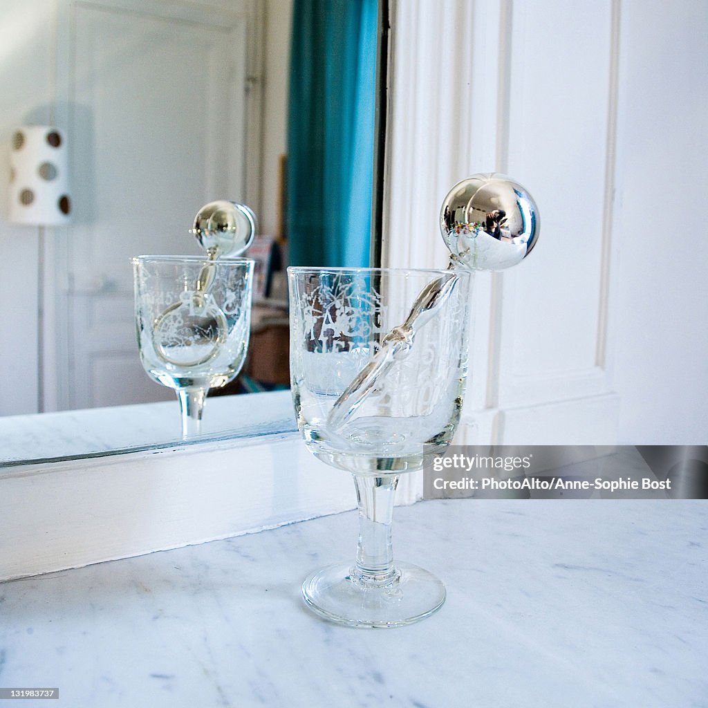 Silver rattle in stemmed glass in front of mirror