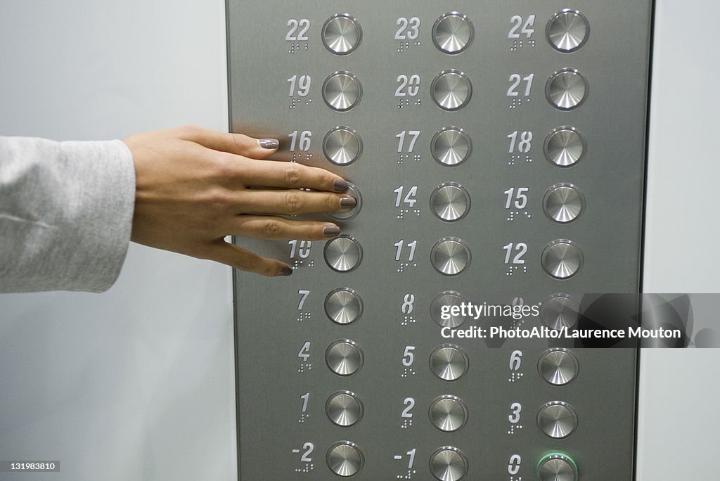 Woman's hand pressing elevator button, cropped