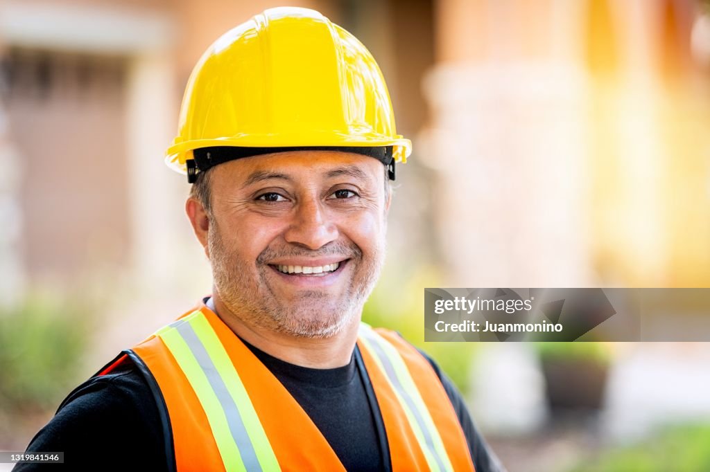 Smiling hispanic construction worker wearing a work helmet looking at the camera