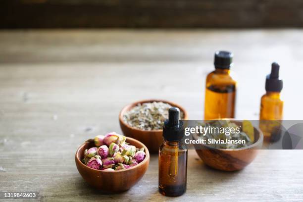 dried herbs in wooden bowls and pipette bottle:  aromatherapy concept - essence stock pictures, royalty-free photos & images