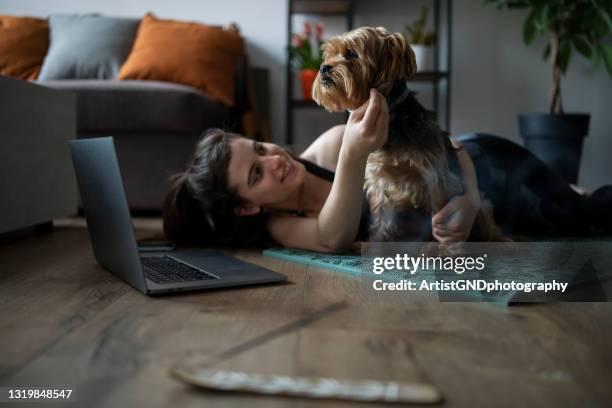 junge frau mit einem laptop, der auf dem boden liegt. - yoga down dog stock-fotos und bilder