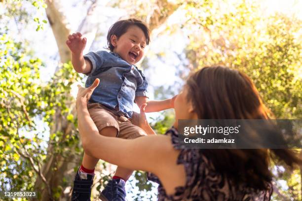 mamá levantando a su hijo en el aire - toddler boy fotografías e imágenes de stock