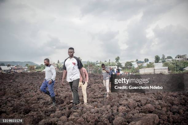 People walk through cooled lava in the aftermath of the eruption of the Nyiragongo volcano on May 24, 2021 in Goma, Democratic Republic of Congo....