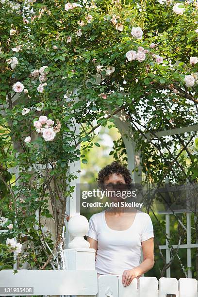 smiling hispanic woman standing underneath trellis - garden gate rose stock pictures, royalty-free photos & images