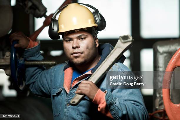 mixed race worker in hard-hat holding large wrench - open end spanner stock pictures, royalty-free photos & images