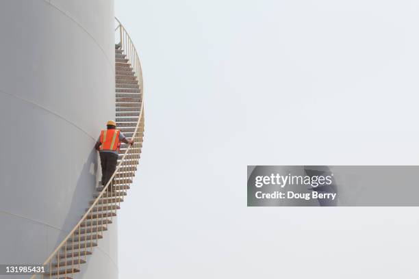 mixed race worker climbing staircase on storage tank - man taking a big step stock pictures, royalty-free photos & images
