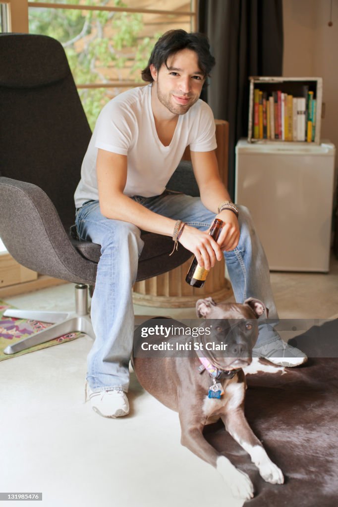 Mixed race man drinking beer and sitting with dog