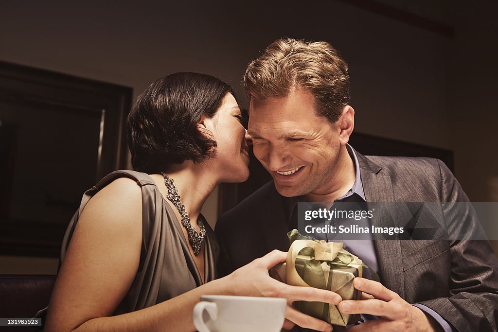 Caucasian man giving woman gift in restaurant