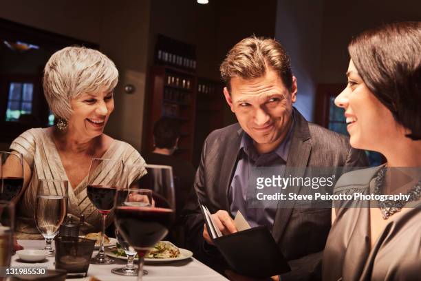 friends eating together in restaurant - paying for dinner imagens e fotografias de stock