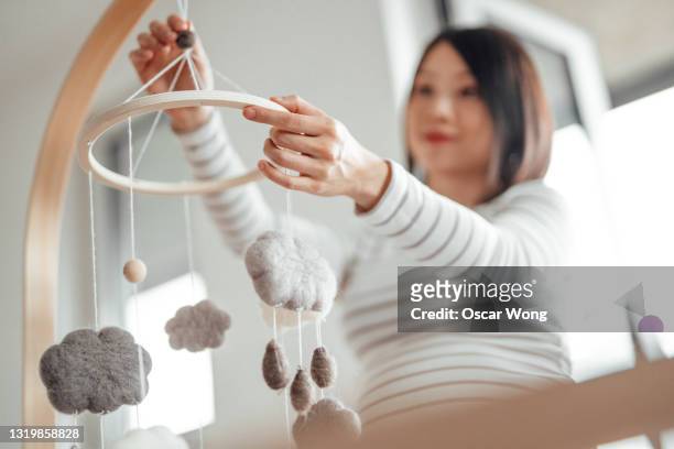 pregnant woman holding a cot mobile toy, preparing nursery bedroom - attrezzatura per neonato foto e immagini stock