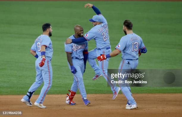 Adolis Garcia of the Texas Rangers and teammates Jose Trevino, Isiah Kiner-Falefa and Joey Gallo celebrate Garcia's game inning walk-off RBI single...