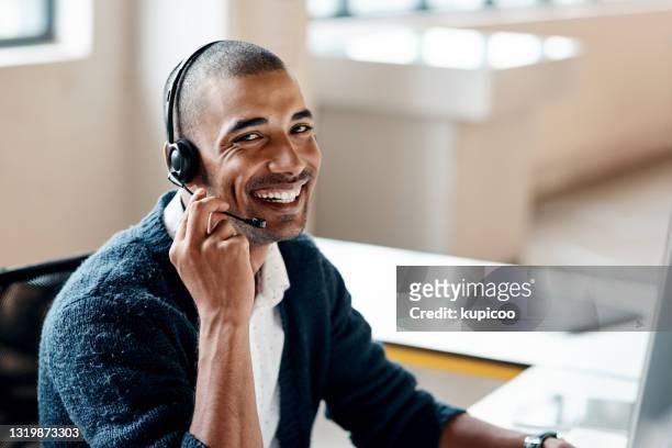 portret van een jonge zakenman die een hoofdtelefoon draagt terwijl het werken in een bureau - klant stockfoto's en -beelden