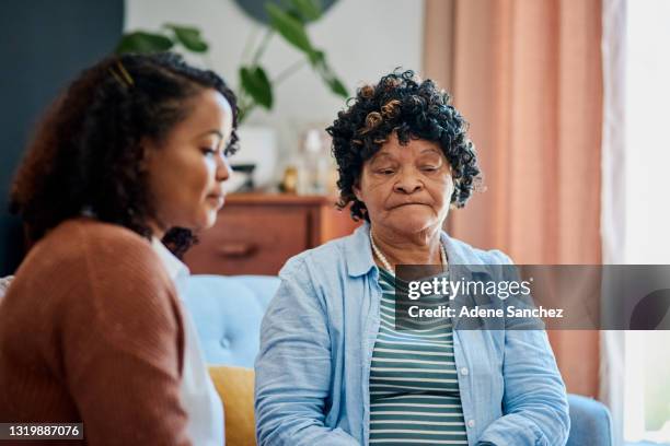 foto de una anciana sentada con su hija en el sofá de su casa y sin hablar - lucho en familia fotografías e imágenes de stock