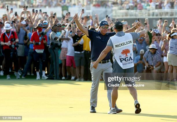 Phil Mickelson of the United States celebrates with brother and caddie Tim Mickelson on the 18th green after winning the 2021 PGA Championship held...