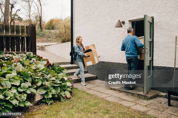 smiling young woman carrying box with father at back yard - back yard photos et images de collection
