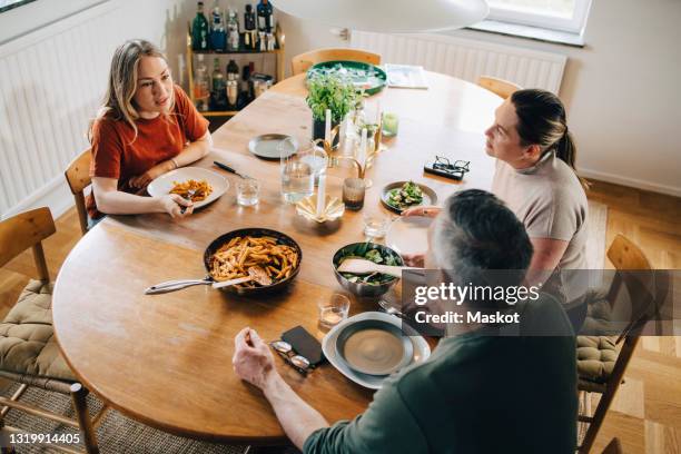 mature parents talking while eating lunch with daughter at home - boomerang generation stock pictures, royalty-free photos & images