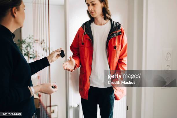 mature woman giving car key to son at home - handing over keys stock pictures, royalty-free photos & images