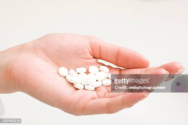 pilules blanches - hand holding several pills photos et images de collection