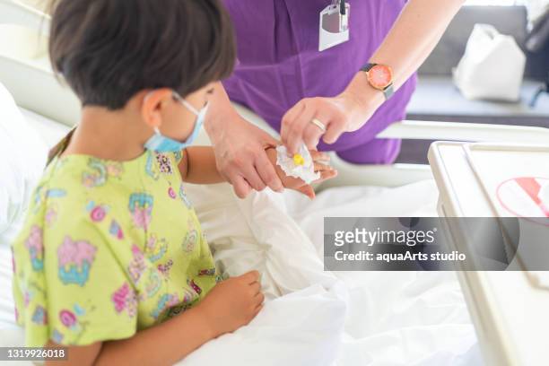 nurse removing iv from the hand of a little patient child on hospital bed - sickness absence stock pictures, royalty-free photos & images