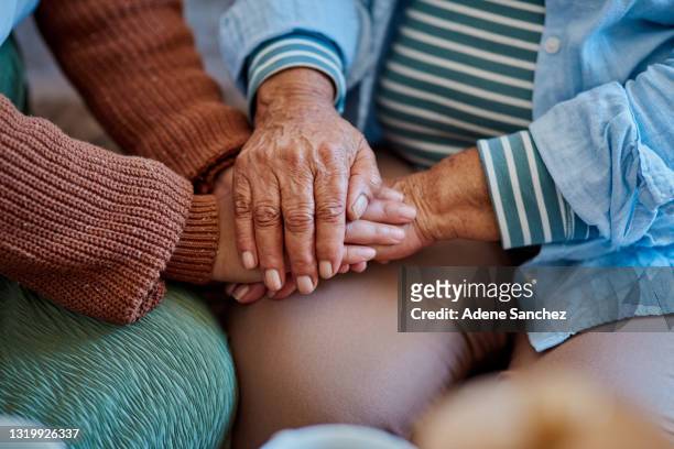 foto de una mujer irreconocible tomado de la mano con su pariente mayor en el sofá de su casa - anciano llorando fotografías e imágenes de stock