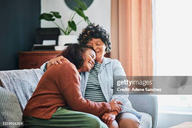 shot of an elderly woman relaxing with her daughter on the sofa at home - mother daughter couch imagens e fotografias de stock