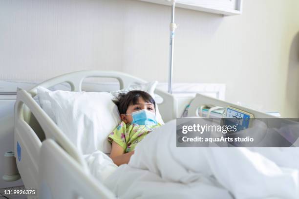 little child patient with protective face mask lying on bed at hospital - illness hospital stock pictures, royalty-free photos & images