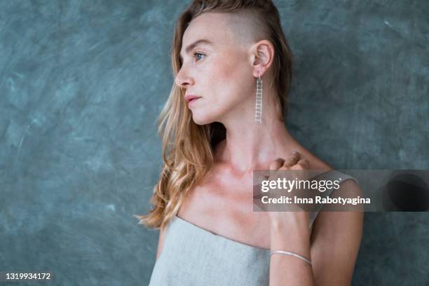 beautiful blonde woman with long silver earring - capelli rasati su un lato foto e immagini stock