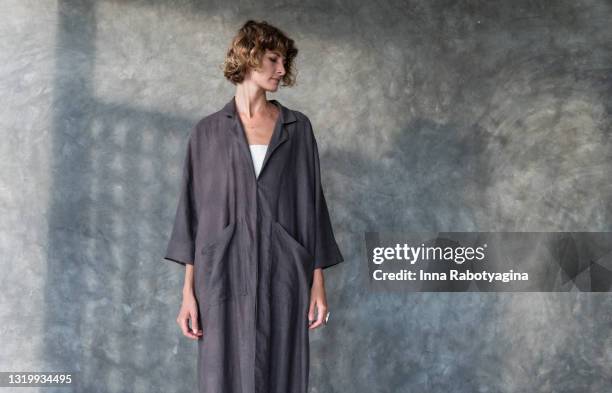 young woman model standing relaxed in long grey jacket - vestuário monocromo imagens e fotografias de stock