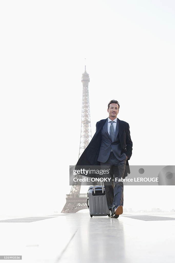 Businessman walking with luggage with the Eiffel Tower in the background, Paris, Ile-de-France, France