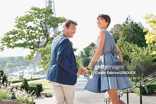 couple moving down steps in the garden with the eiffel tower in the background, paris, ile-de-france, france - couple paris stock pictures, royalty-free photos & images