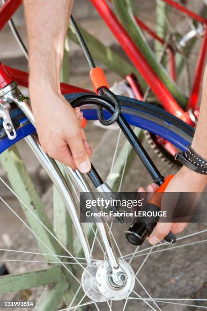close-up of a man's hands locking his bicycle, paris, ile-de-france, france - fahrradschloss stock-fotos und bilder