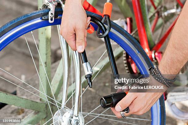 close-up of a man's hands locking his bicycle, paris, ile-de-france, france - fahrradschloss stock-fotos und bilder