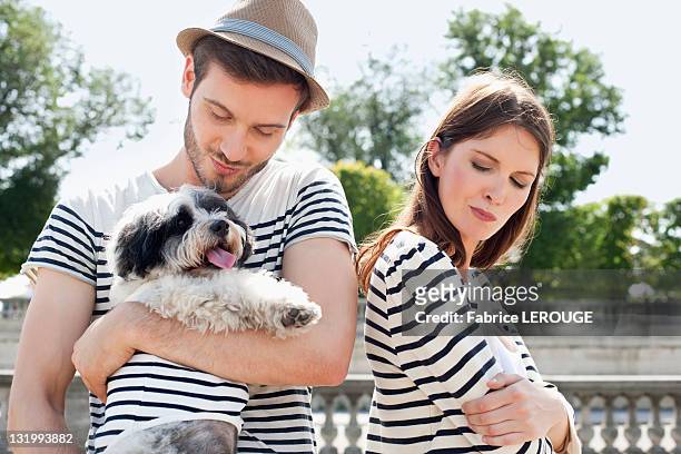 man carrying a puppy and smiling with a woman looking sad, paris, ile-de-france, france - zeemansstrepen stockfoto's en -beelden