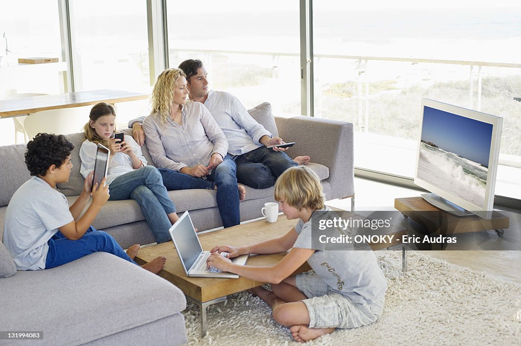 Couple watching television set while their children busy in different activities