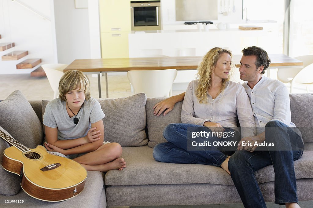 Teenage boy sitting with a guitar on a couch