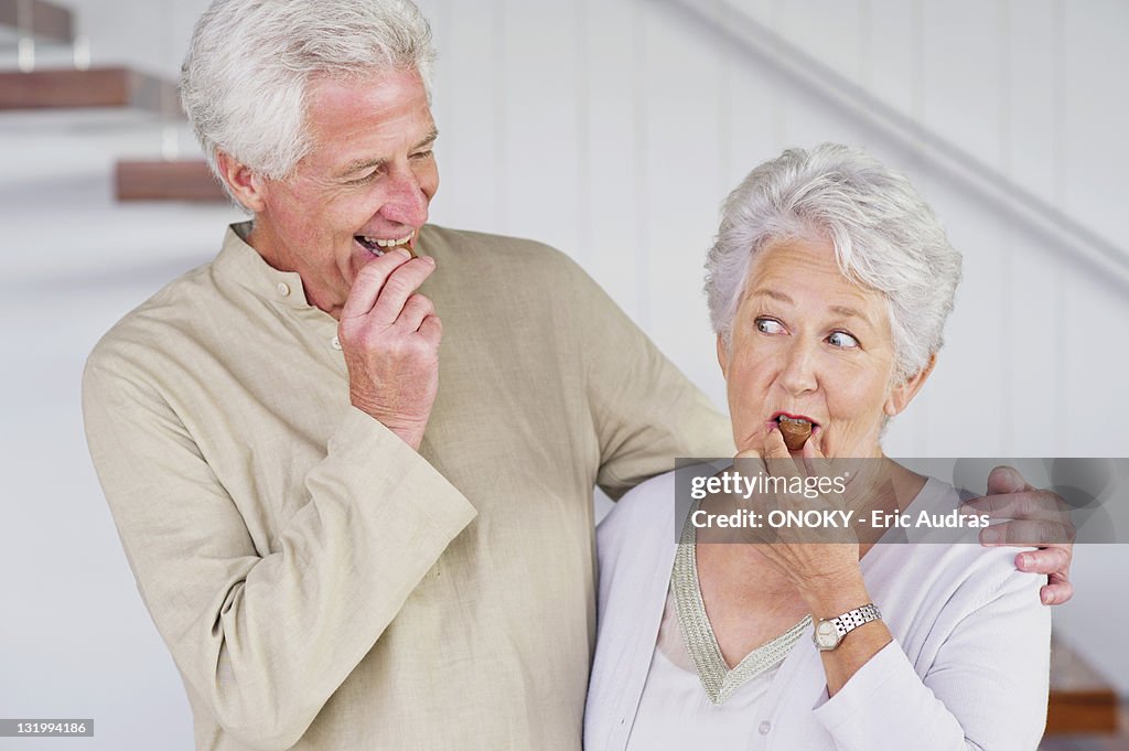 Senior couple eating chocolate at home
