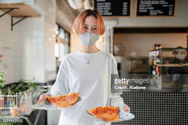 マスクを着用したピザスライスを持つ笑顔のウェイトレスの肖像画 - 飲食店 ストックフォトと画像