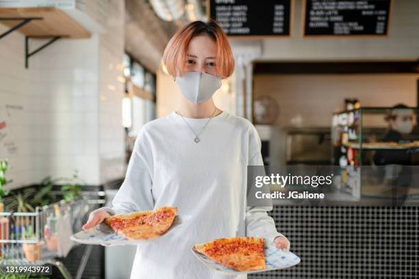 portrait of a smiling waitress holding pizza slices wearing a mask - restaurant mask stock pictures, royalty-free photos & images