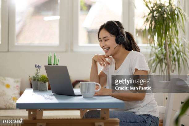 young happy woman of mongolian ethnicity working as a customer support - smart working stock pictures, royalty-free photos & images